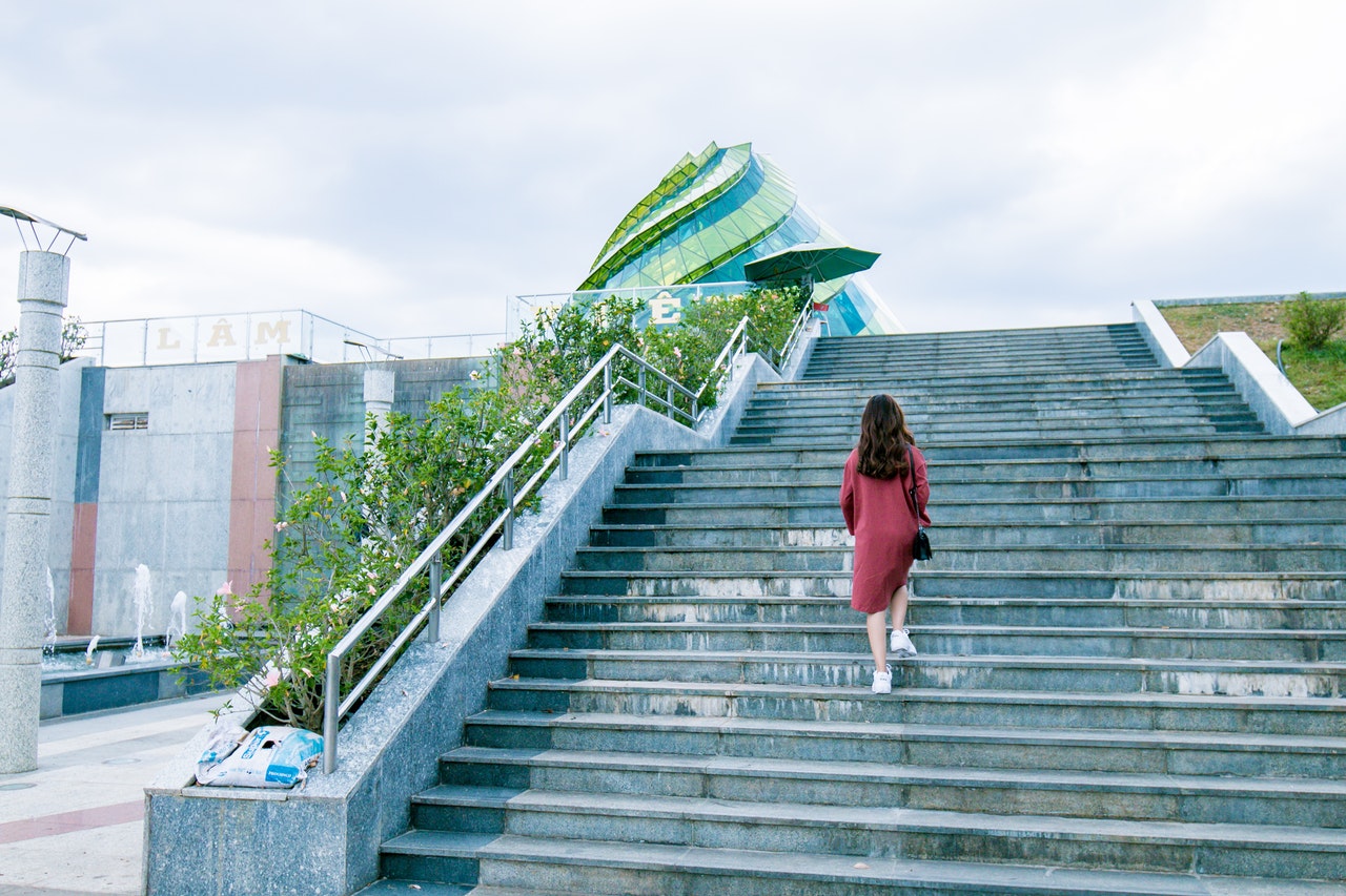 A woman walks up a large set of outdoor stairs with confidence.