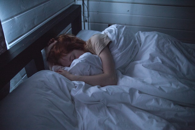 A young woman curls up in bed to get a good night's sleep.
