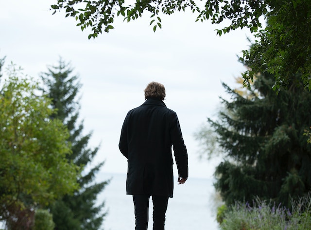 A man dressed in black stands alone in the distance, his back to the camera.